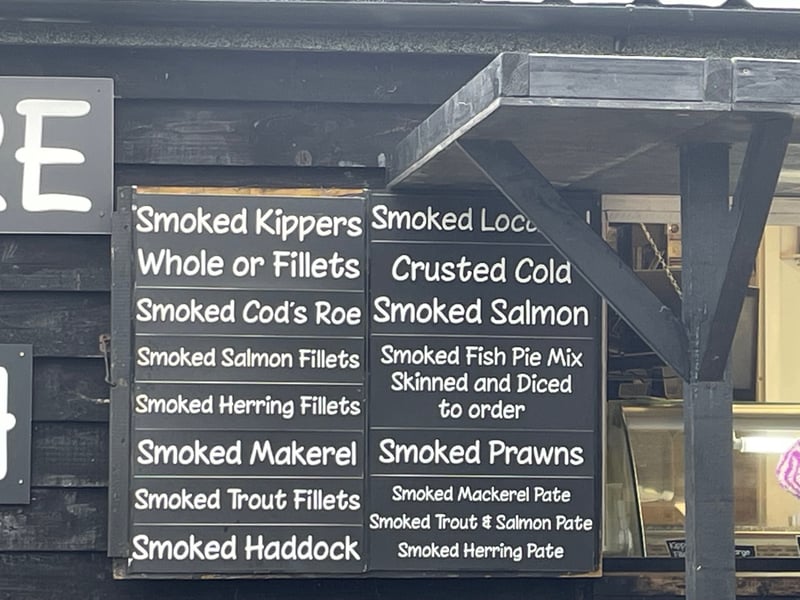 smoked fish menu board on the side of a hut